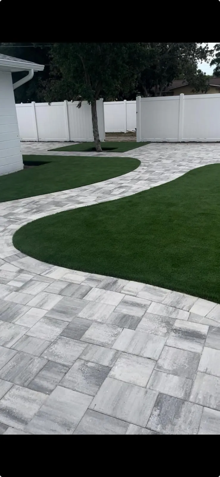 Hexagonal paver patio with artificial turf beside a pool