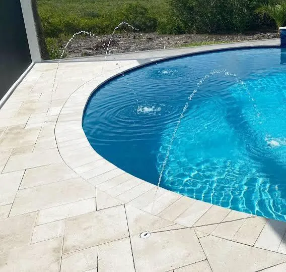 Travertine pool deck with curved coping and water deck jets